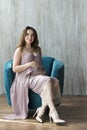 A young pregnant woman in a purple dress sitting on a chair. Royalty Free Stock Photo