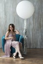 A young pregnant woman in a purple dress sitting on a chair. Royalty Free Stock Photo
