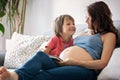 Young pregnant woman, reading a book at home to her boy Royalty Free Stock Photo