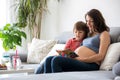 Young pregnant woman, reading a book at home to her boy Royalty Free Stock Photo
