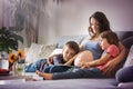 Young pregnant woman, reading a book at home to her two boys Royalty Free Stock Photo