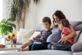 Young pregnant woman, reading a book at home to her two boys Royalty Free Stock Photo