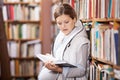 Young pregnant woman reading book