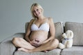 Young pregnant woman relaxing on couch with a teddy bear Royalty Free Stock Photo