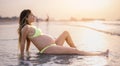 Young pregnant woman relaxing on sandy beach at sunset. Royalty Free Stock Photo