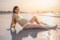 Young pregnant woman relaxing on sandy beach at sunset. Royalty Free Stock Photo