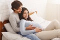 Young pregnant woman resting in bed with her husband