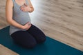 Young pregnant woman sat on mat doing prenatal yoga holding belly Royalty Free Stock Photo