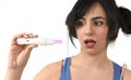 Young pregnant woman scared in shock checking pink positive result on pregnancy test