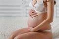 Young pregnant woman sits on the bed turning sideways Royalty Free Stock Photo