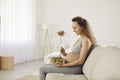 Young pregnant woman sitting on couch and eating bowl of healthy vegetable salad Royalty Free Stock Photo