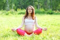 Young pregnant woman sitting on grass doing yoga exercise Royalty Free Stock Photo