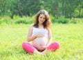 Young pregnant woman sitting on grass doing yoga Royalty Free Stock Photo