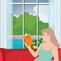 Young pregnant woman sitting on sofa and reading a book Royalty Free Stock Photo