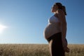 Young Pregnant Woman Standing in an Open Field