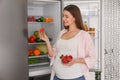 Young pregnant woman with strawberries near fridge at home. Healthy eating Royalty Free Stock Photo