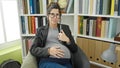 Young pregnant woman student holding book touching belly at library university Royalty Free Stock Photo