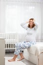 A young pregnant woman is suffering from a headache. Children`s room in the background. Concept of pregnant women`s health, Royalty Free Stock Photo