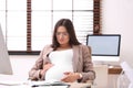 Young pregnant woman suffering from pain while working Royalty Free Stock Photo