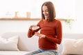 Young pregnant woman taking vitamins pills sitting in living room Royalty Free Stock Photo