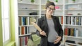Young pregnant woman teacher holding clipboard touching belly at library university Royalty Free Stock Photo