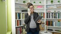 Young pregnant woman teacher using touchpad talking on smartphone at library university Royalty Free Stock Photo