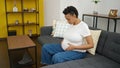 Young pregnant woman touching belly sitting on sofa with sad expression at home Royalty Free Stock Photo