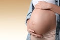 Young pregnant woman touching her belly on beige background, closeup. Space for text Royalty Free Stock Photo