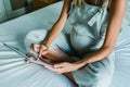 Young pregnant woman using a digital tablet while resting on bed at home Royalty Free Stock Photo