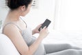 Young pregnant woman using smartphone with blank screen lying on bed. Royalty Free Stock Photo