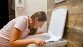 Young pregnant woman vomitting and suffering from nausea in toilet holding positive pregnancy test. Intoxication and