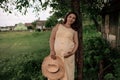 Young pregnant woman walking in the green field on a sunny summer day. Nature in the country. Royalty Free Stock Photo