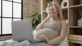 Young pregnant woman watching video on laptop lying on bed at bedroom Royalty Free Stock Photo