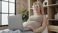 Young pregnant woman watching video on laptop lying on bed at bedroom Royalty Free Stock Photo