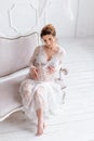 Young pregnant woman wearing lace dress in white interior. Fashion shot. Royalty Free Stock Photo