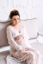 Young pregnant woman wearing lace dress in white interior. Fashion shot. Royalty Free Stock Photo