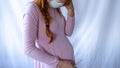 A young pregnant woman is wearing a mask and staying sick at home