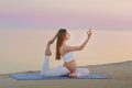 Young pregnant woman in white dress sitting on the beach near blue sea and breathing. Summer vacation during pregnancy Royalty Free Stock Photo