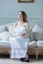 Young pregnant woman in white dress sitting Royalty Free Stock Photo