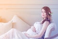 Young pregnant woman in white dress sitting Royalty Free Stock Photo