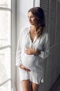 Young pregnant woman in white dress in the studio Royalty Free Stock Photo