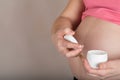 Young pregnant woman keeps skin cream care close to her belly Royalty Free Stock Photo