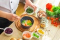 Young prepares a poke bowl in a modern kitchen. The man prepares food at home. Cooking healthy and tasty food.