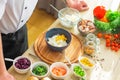 Young prepares a poke bowl in a modern kitchen. The man prepares food at home. Cooking healthy and tasty food.