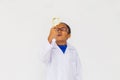 Young preteen African American kid wearing lab coat looking up with magnifier