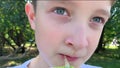 A young preteen caucasian boy sitting in summer city park and drinking juice through a straw from the paper juice pack, close up Royalty Free Stock Photo