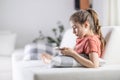 Young preteen girl looks into her phone while having comfortable time at home Royalty Free Stock Photo