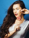 Young pretty adorable brunette woman with candy close up posing on blue background, like doll makeup, fashion beauty Royalty Free Stock Photo