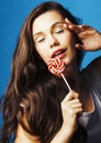 Young pretty adorable brunette woman with candy close up posing on blue background, like doll makeup, fashion beauty Royalty Free Stock Photo