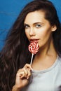 Young pretty adorable brunette woman with candy close up posing on blue background, like doll makeup, fashion beauty Royalty Free Stock Photo